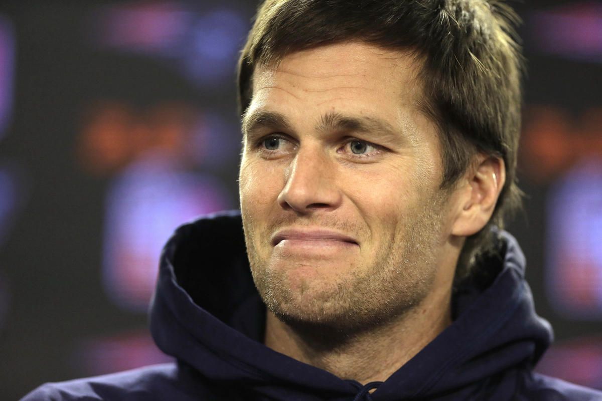 New England Patriots quarterback Tom Brady smiles while facing reporters before a scheduled NFL football practice, Wednesday, Jan. 6, 2016, in Foxborough, Mass. The Patriots are to host an NFL divisional playoff game Jan. 16, 2016, in Foxborough, Mass. (AP Photo/Steven Senne)